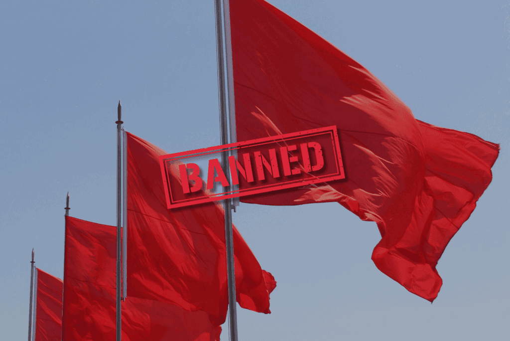 Multiple red flags waving against a clear sky, overlaid with the word "BANNED", representing Texas’ 2025 ban on red-flag gun laws.