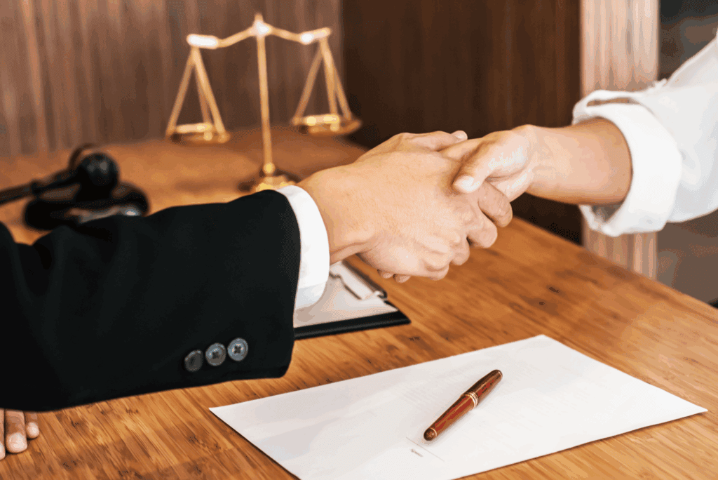 Attorney and client shaking hands during a legal consultation, symbolizing support and representation.